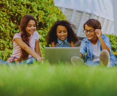 elementary-aged students outside, using tablets
