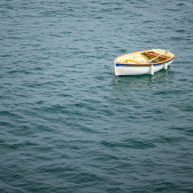A single wooden rowboat floating on calm water, surrounded by soft, muted tones, symbolizing drift off course.