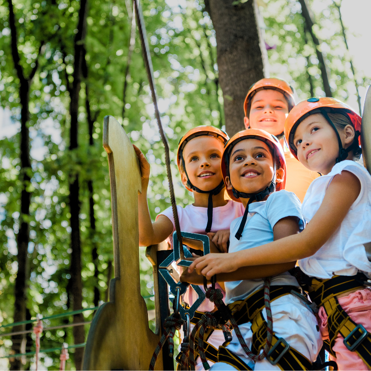 Children navigating a ropes course in a forest.