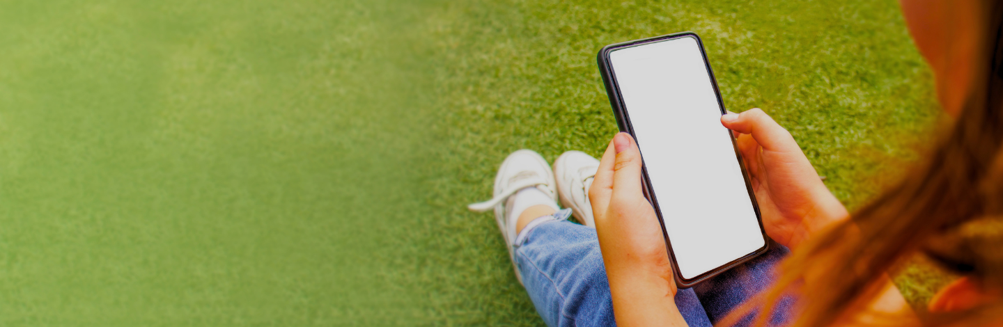 Student sitting on grass holding tablet