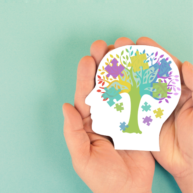 Hands holding a paper head with a colorful tree and puzzle pieces inside.