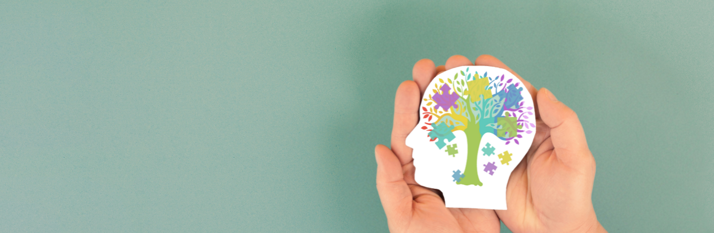 Hands holding a paper head with a colorful tree and puzzle pieces inside.