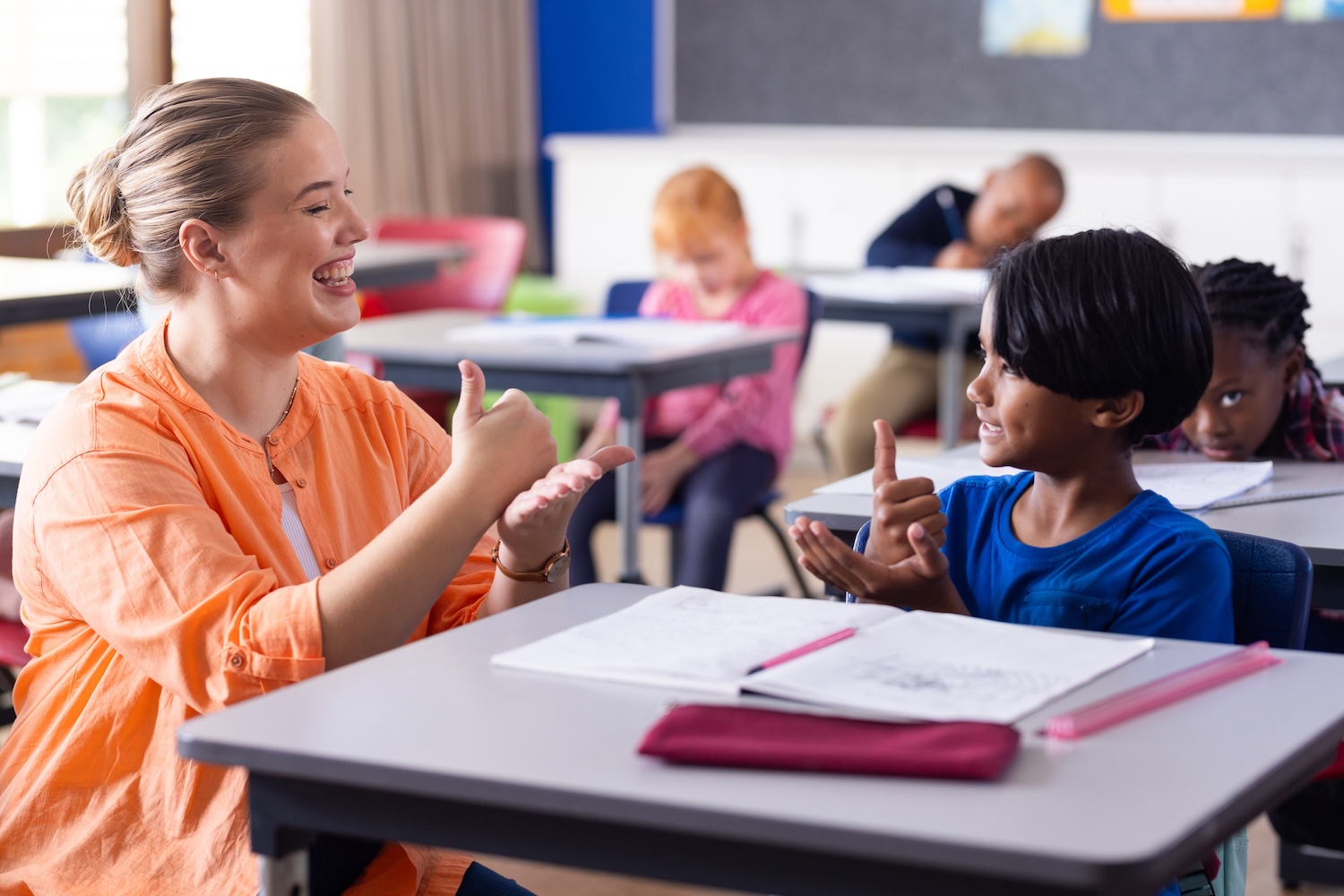 Smiling female teacher, smiling student, sign language